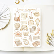 Premium Handmade Sticker Sheet Dark & Light Academia 105mm x 148mm - a sheet on the table with an opened notebook, a white flower branch