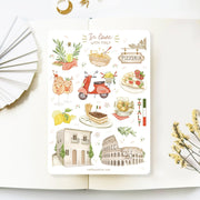 Premium Handmade Sticker Sheet In Love With Italy 105mm x 148mm - a sheet on the table with a white flower branch, an opened notebook