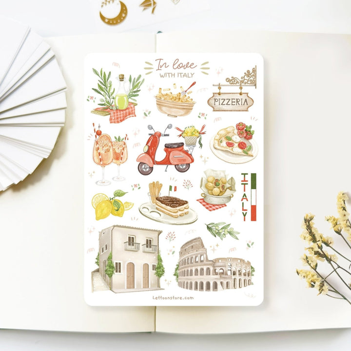 Premium Handmade Sticker Sheet In Love With Italy 105mm x 148mm - a sheet on the table with a white flower branch, an opened notebook