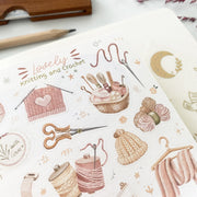 Premium Handmade Sticker Sheet Knitting Crochet 105mm x 148mm - a sheet on the table with a dark maroon flower branch, an opened notebook, a pencil, a ruler