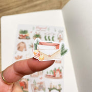 Premium Handmade Sticker Sheet Magical Cozy Winter 105mm x 148mm - a piece and a sheet on the table with an opened notebook