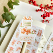 Premium Handmade Sticker Sheet Present Time 105mm x 148mm - apiece on stick and a sheet on the table with a red berry branch, a plant branch, an opened notebook
