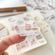 Premium Handmade Sticker Sheet Reading at Home 105mm x 148mm - a piece on the finger and a sheet on the table with a dark maroon flower branch, an opened notebook, a pencil, a ruler