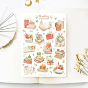 "Premium Handmade Sticker Sheet 
Reading in the Winter 105mm x 148mm - a sheet on the table with a white flower branch, an opened notebook"