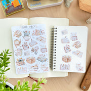 Premium Handmade Sticker Sheet Reading Time 105mm x 148mm - 9 pieces and a sheet on the table with a plant pot, an opened notebook
