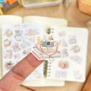 Premium Handmade Sticker Sheet Reading Time 105mm x 148mm - a piece and 2 sheets on the table with an opened notebook in the background