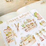 Premium Handmade Sticker Sheet 
Veggie Garden 105mm x 148mm - a sheet on the table with a white flower branch, an opened notebook