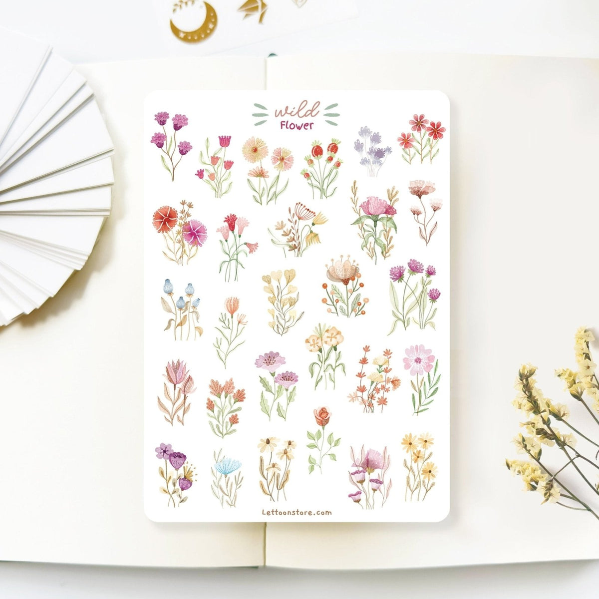 Premium Handmade Sticker Sheet Wild Flower 105mm x 148mm - a sheet on the table with a white flower branch, an opened notebook