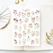 Premium Handmade Sticker Sheet Wild Flower 105mm x 148mm - a sheet on the table with a white flower branch, an opened notebook