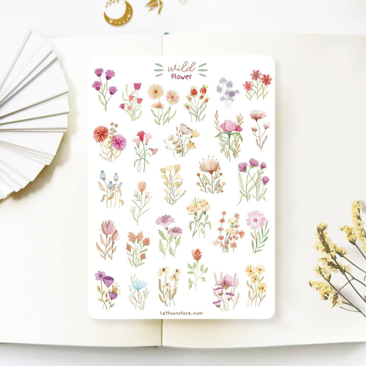 Premium Handmade Sticker Sheet Wild Flower 105mm x 148mm - a sheet on the table with a white flower branch, an opened notebook