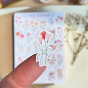 Premium Handmade Sticker Sheet Wild Flower 105mm x 148mm - a piece on the finger and a sheet on the table with a white flower branch, an opened notebook