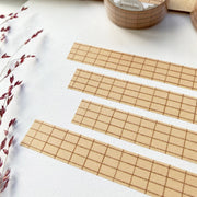 Premium Handmade Washi Tape Brown Grid 15mm x 10m - 4 pieces and a washi tape on the table with a dark maroon flower branch