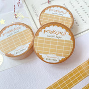 Premium Handmade Washi Tape Butterscotch Grid 15mm x 10m - a piece and 3 washi tapes on the table with a dark maroon flower branch, a sticker sheet, a chapter heading