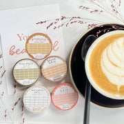 Premium Handmade Washi Tape Butterscotch Grid 15mm x 10m - 5 washi tapes on the table with 2 dark maroon flower branches, a sticker sheet, a chapter heading, a cup of latte with spoon