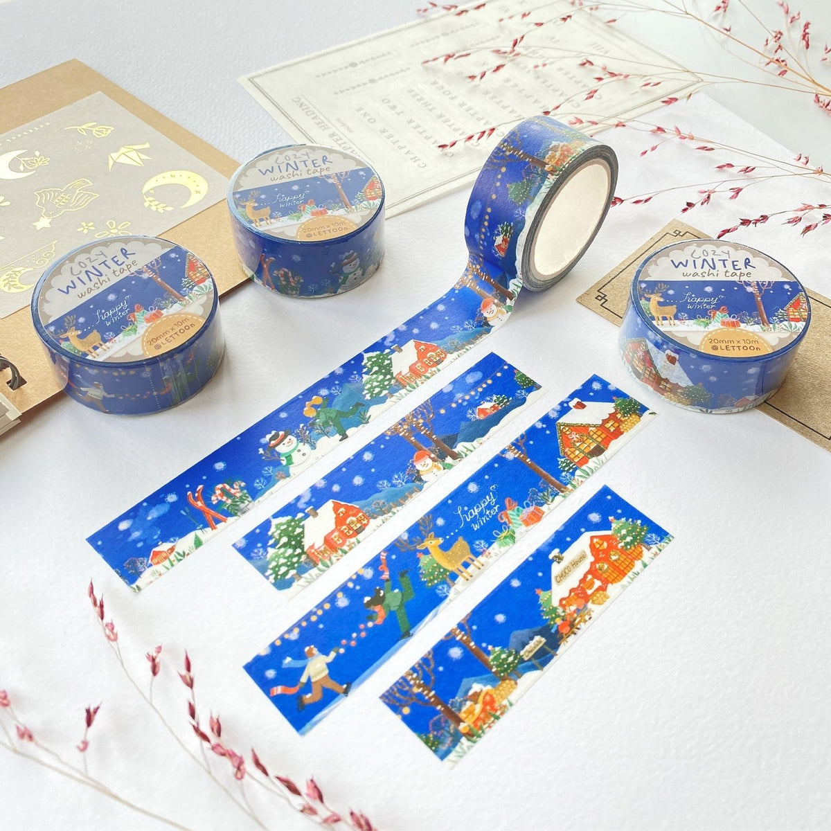 Premium Handmade Washi Tape Cozy Winter 20mm x 10m - 4 pieces and 4 washi tapes on the table with 2 dark maroon flower branches, a sticker sheet, a chapter heading, a notebook