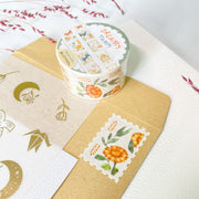 Premium Handmade Washi Tape Dreamy Stamp 25mm x 5m - a piece and a washi tape on the table with a pink flower branch, an envelope, a sticker sheet