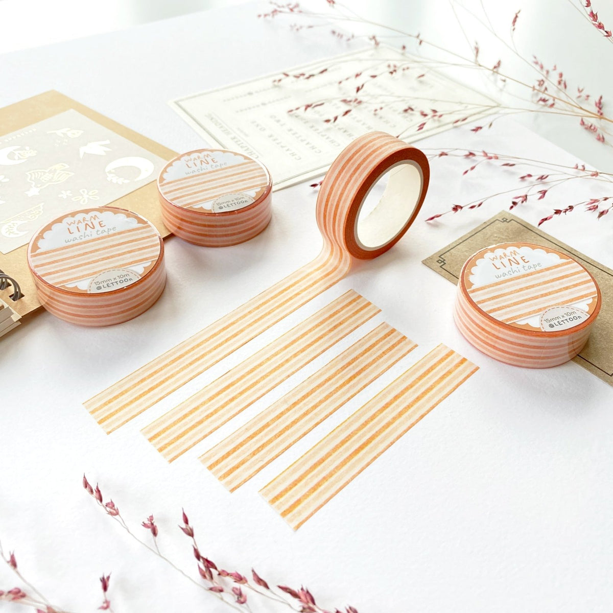 Premium Handmade Washi Tape Warm Line 15mm x 10m - 4 pieces and 4 washi tapes on the table with 2 dark maroon flower branches, a sticker sheet, a chapter heading