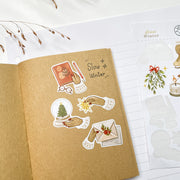 Slow Winter stickers in a kraft notebook: a snow globe, a sealed letter and a lit candle
