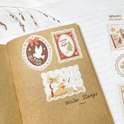 Winter Stamps stickers in a kraft notebook: a dove stamp, a merry and bright stamp and a deer stamp
