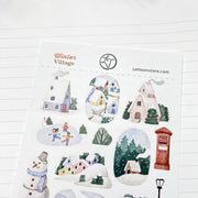Close-up of Winter Village kiss-cut stickers on matte paper: a red post box and snowy rooftops
