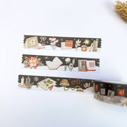 Three strips of Cozy Mind Winter Days washi tape, on near-black: a writing desk with notebooks, a desk lamp, letter tiles and poinsettia