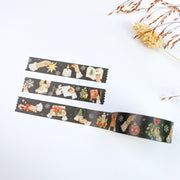 Three strips of Slow Winter washi tape, on near-black with snowflakes: hands lighting a candle, hanging a bauble and writing letters