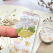 Premium Handmade Sticker Sheet A Day At Home 105mm x 148mm - a piece on the finger and a sheet on the table with a white flower branch, a purple flower branch, a washi tape, an opened notebook