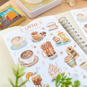Premium Handmade Sticker Sheet Coffee 105mm x 148mm - = sheet on the table with a plant branch, an opened notebook