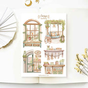 Premium Handmade Sticker Sheet Cozy Scenery 105mm x 148mm - 4 pieces on the table with a white flower branch, a opened notebook