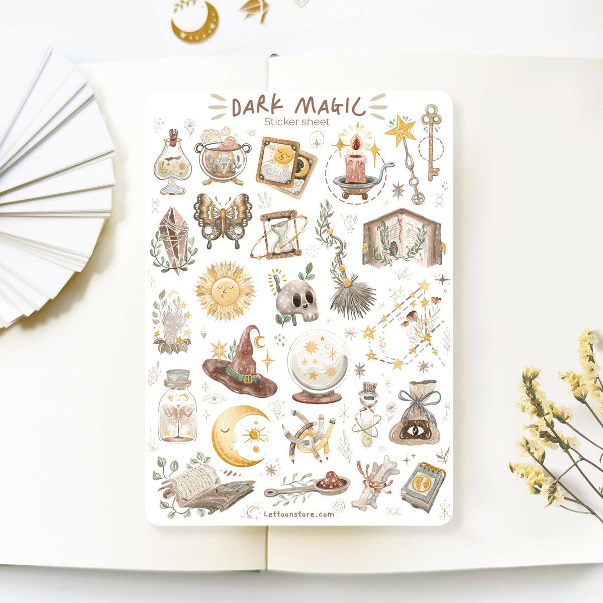Premium Handmade Sticker Sheet Dark Magic 105mm x 148mm - a sheet on the table with a white flower branch, an opened notebook