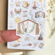 Premium Handmade Sticker Sheet Dark Magic 105mm x 148mm - a piece on the finger and a sheet on the table with a white flower branch, an opened notebook