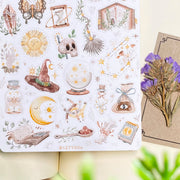 Premium Handmade Sticker Sheet Dark Magic 105mm x 148mm - a sheet on the table with a purple flower branch, an opened notebook