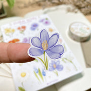 Premium Handmade Sticker Sheet Floral Desire 105mm x 148mm - a piece on the finger and a sheet on the table with a white flower branch, an opened notebook, a washi tape