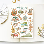 Premium Handmade Sticker Sheet Into The Wild 105mm x 148mm - a sheet on the table with a white flower branch, an opened notebook