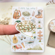 Premium Handmade Sticker Sheet Into The Wild 105mm x 148mm - a piece on the finger and a sheet on the table with a white flower branch, an opened notebook, a washi tape