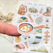 Premium Handmade Sticker Sheet Into The Wild 105mm x 148mm - a piece on the finger and a sheet on the table with a white flower branch, an opened notebook