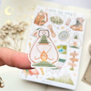Premium Handmade Sticker Sheet Into The Wild 105mm x 148mm - a piece on the finger and a sheet on the table with a white flower branch, an opened notebook