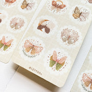 Premium Handmade Sticker Sheet Magic Wings 105mm x 148mm - 3 sheets on the table with an opened notebook