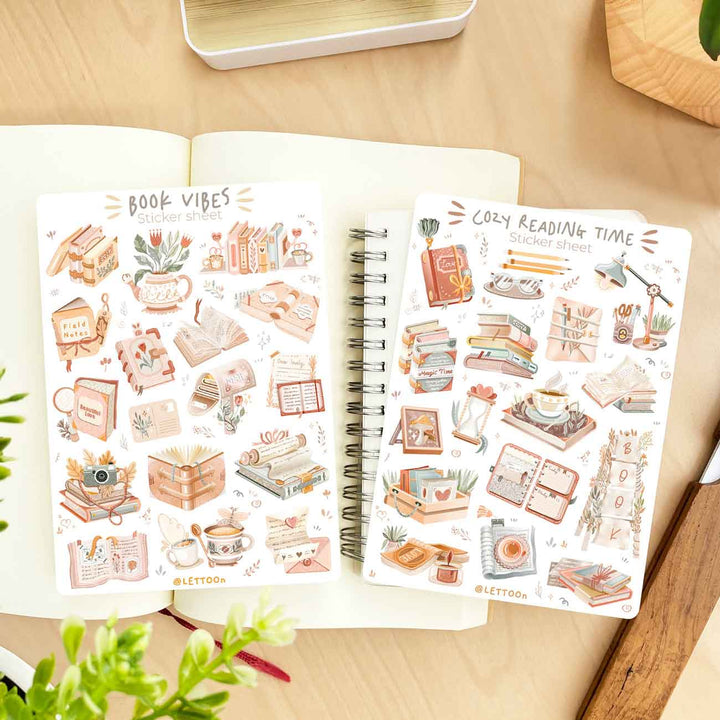 Premium Handmade Sticker Sheet Reading Time 105mm x 148mm - 2 sheets on the table with a plant branch, an opened notebook