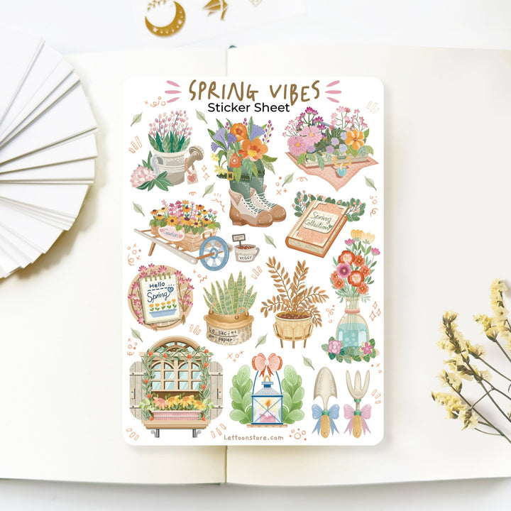 Premium Handmade Sticker Sheet Spring Vibes 105mm x 148mm - a sheet on the table with a white flower branch, an opened notebook