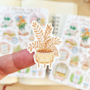 Premium Handmade Sticker Sheet Spring Vibes 105mm x 148mm - a piece on the finger and 2 sheets on the table with an opened notebook