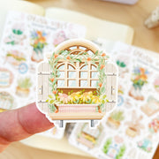 Premium Handmade Sticker Sheet Spring Vibes 105mm x 148mm - a piece on the finger and 2 sheets on the table with an opened notebook